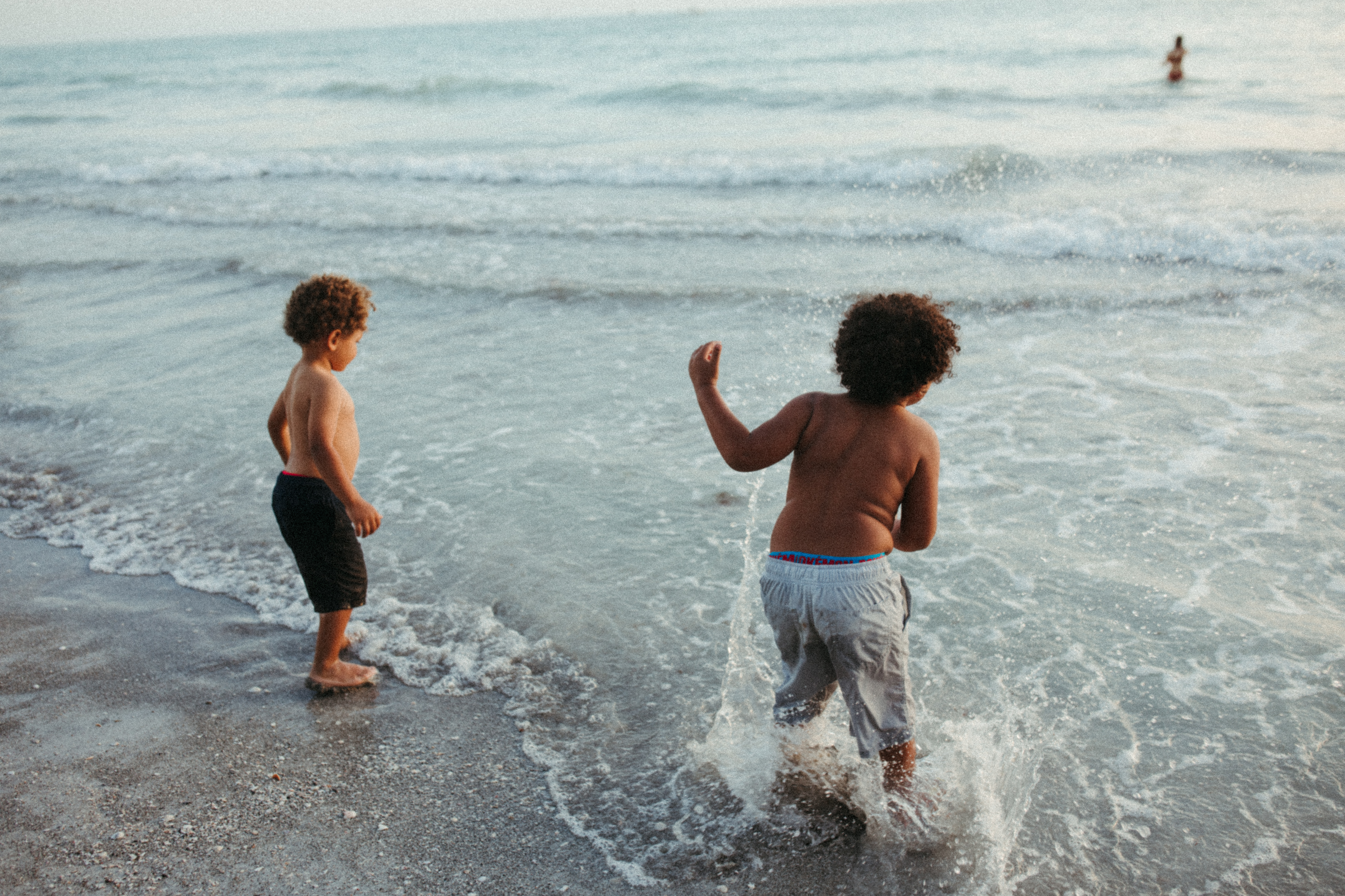 Motherhood and Family Photographer Lauren Neal Photography Two brothers plays in the ocean while they wait for their sister in Venice, Florida