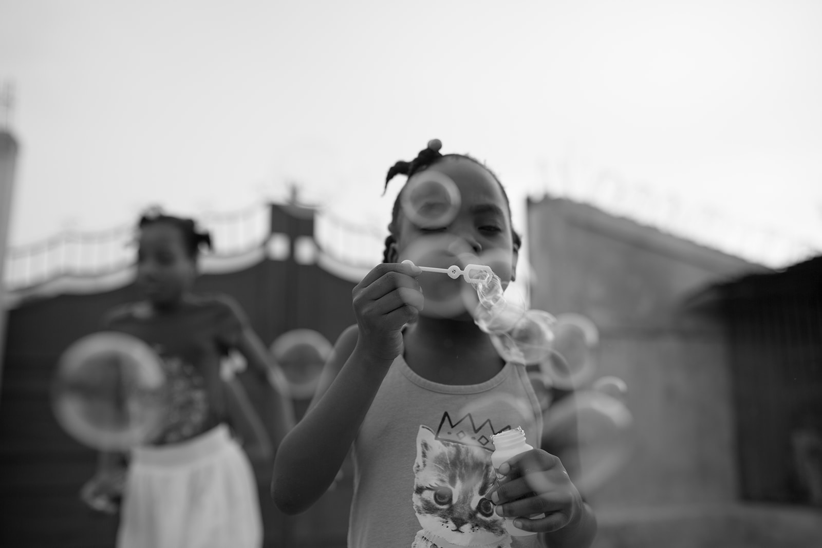 A Haitian child blows bubbles and plays with her friends in Port-au-Prince, Haiti