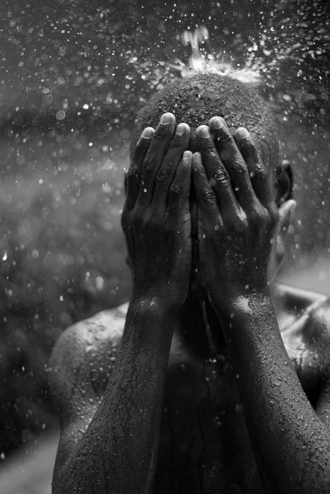 A Haitian boy covers his face with his hands in the rain in Port-au-Prince, Haiti