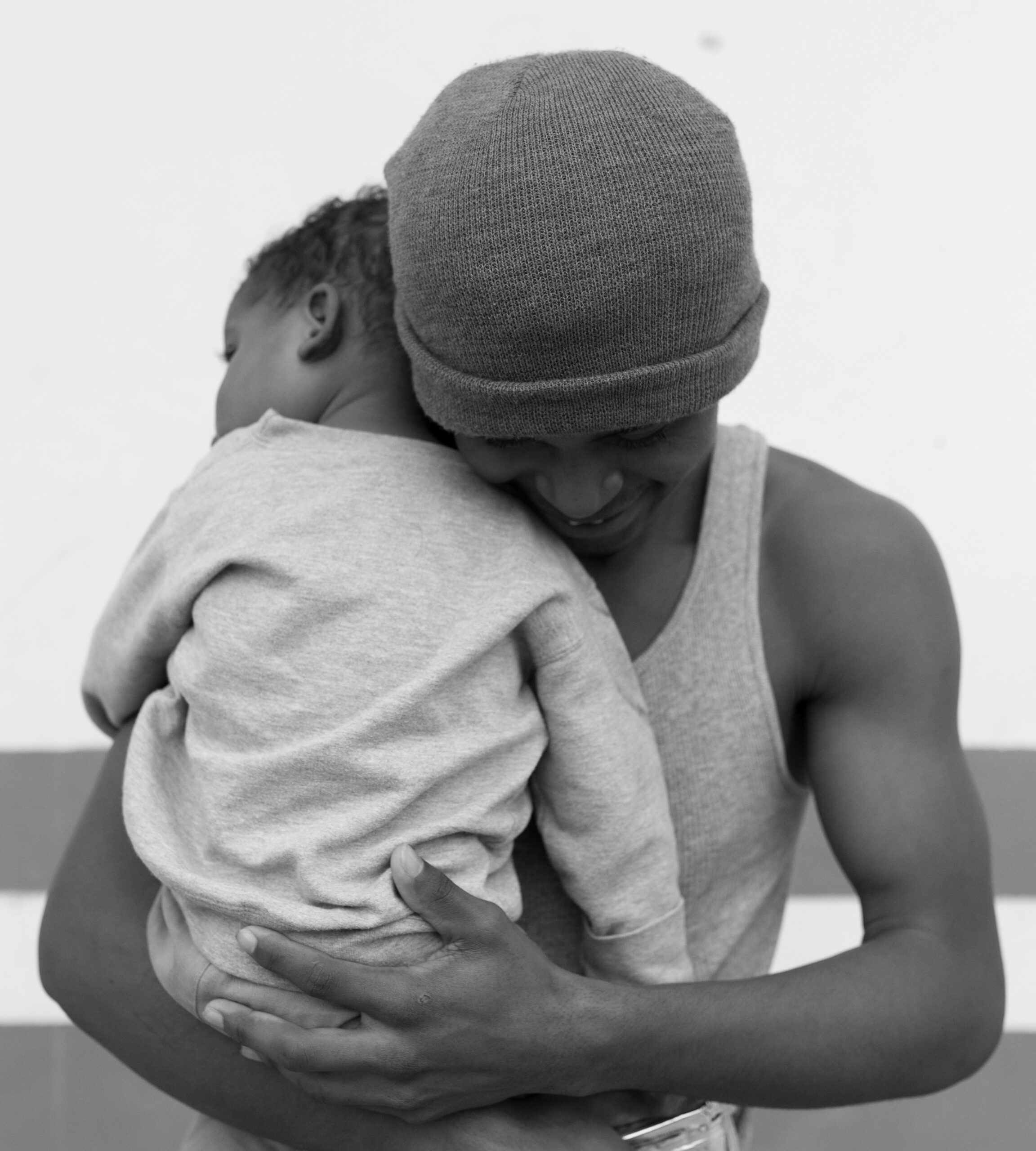 A man holds his child tightly, while living in a migrant shelter on the US Mexico border in Acuña, Mexico.