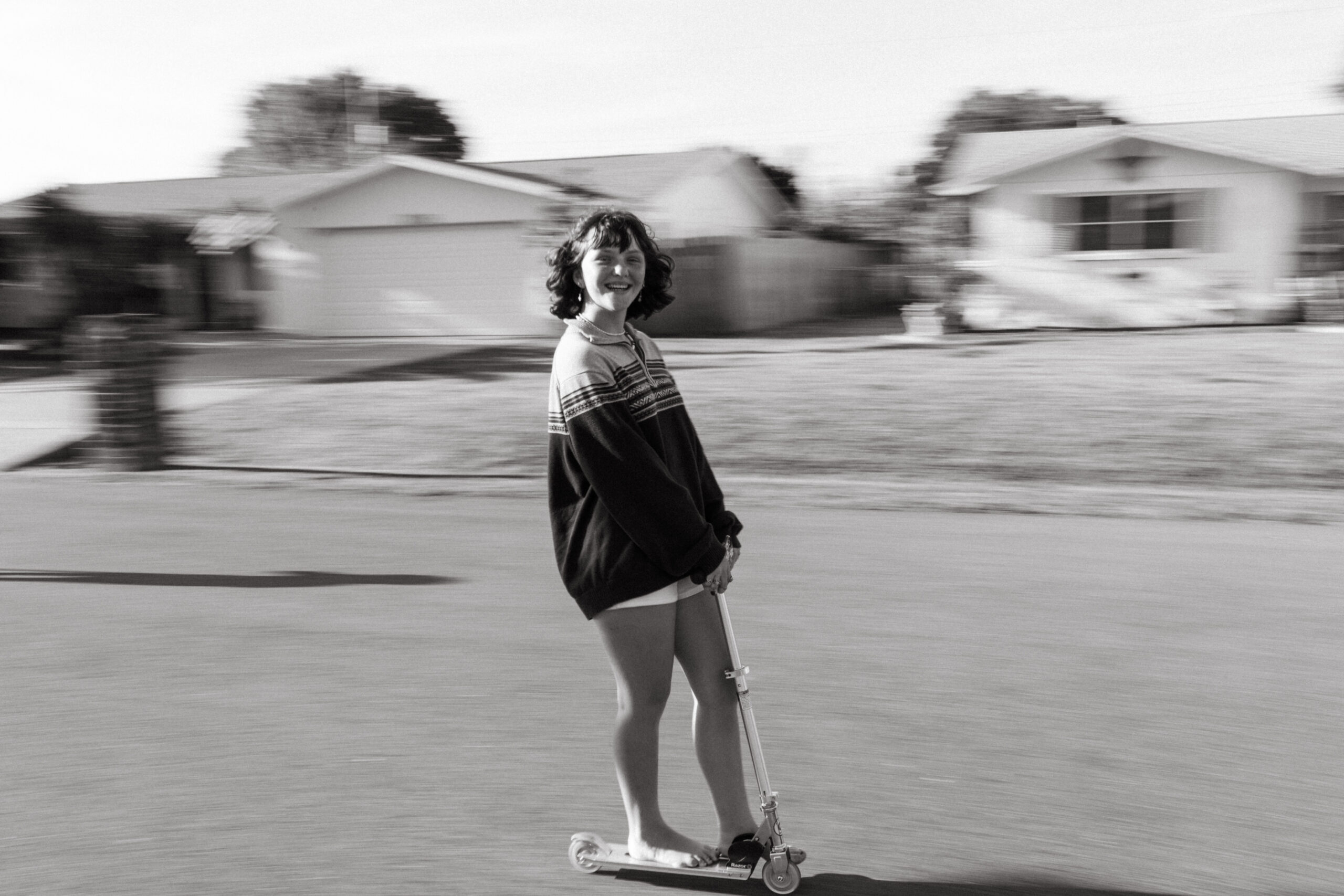Lifestyle Family Photographer from Cincinnati, Ohio Teenage girl rides a scooter on her street