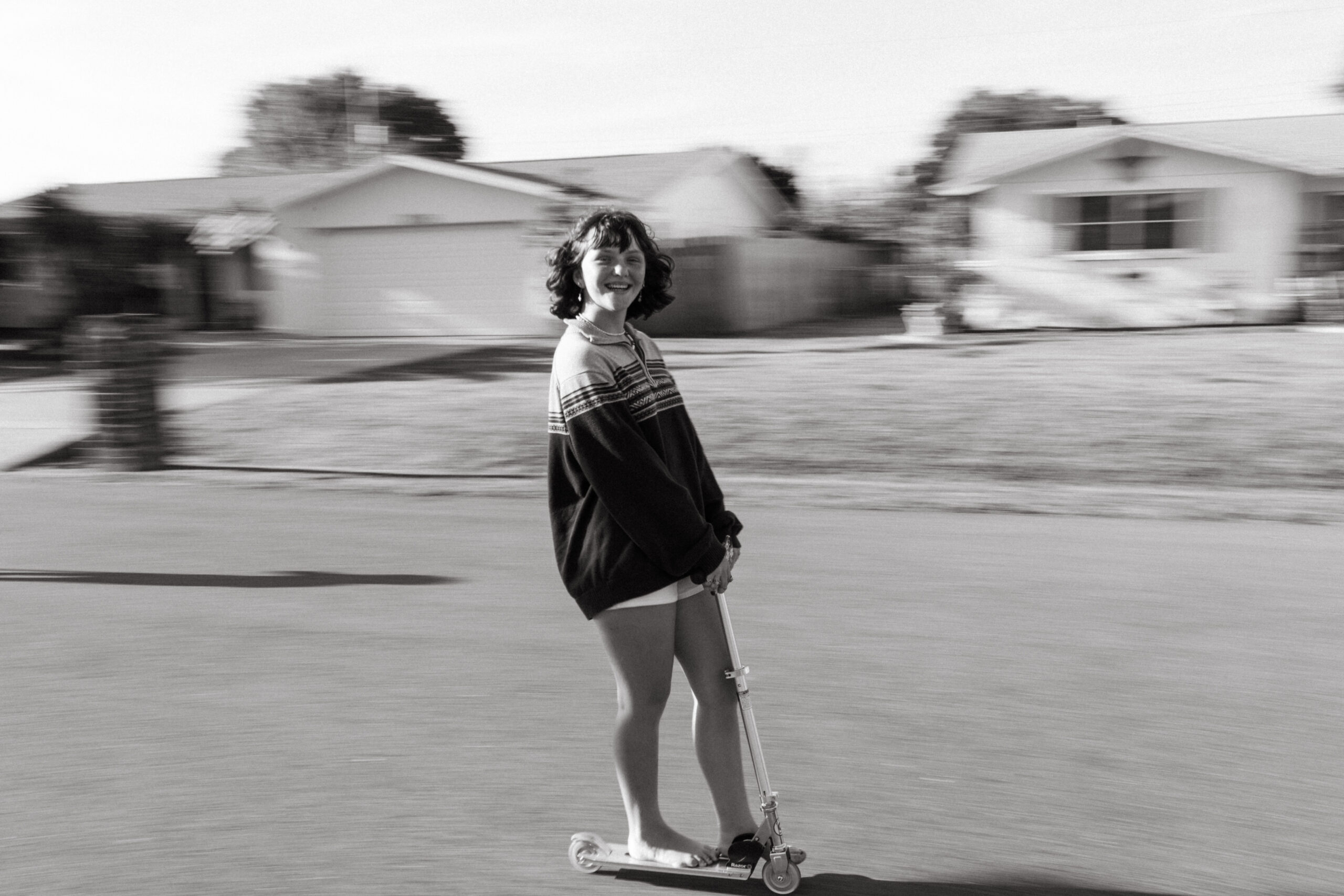 Teenage girl rides a scooter on her street