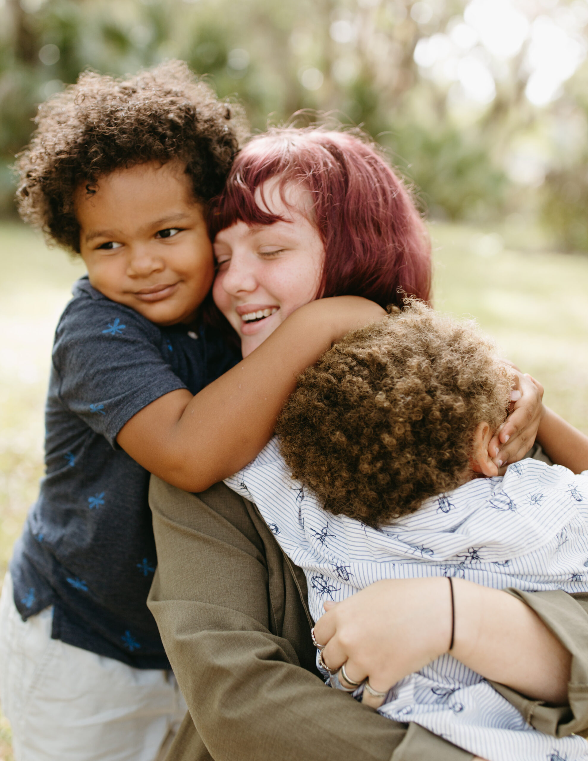 Sister hugs her two younger brothers