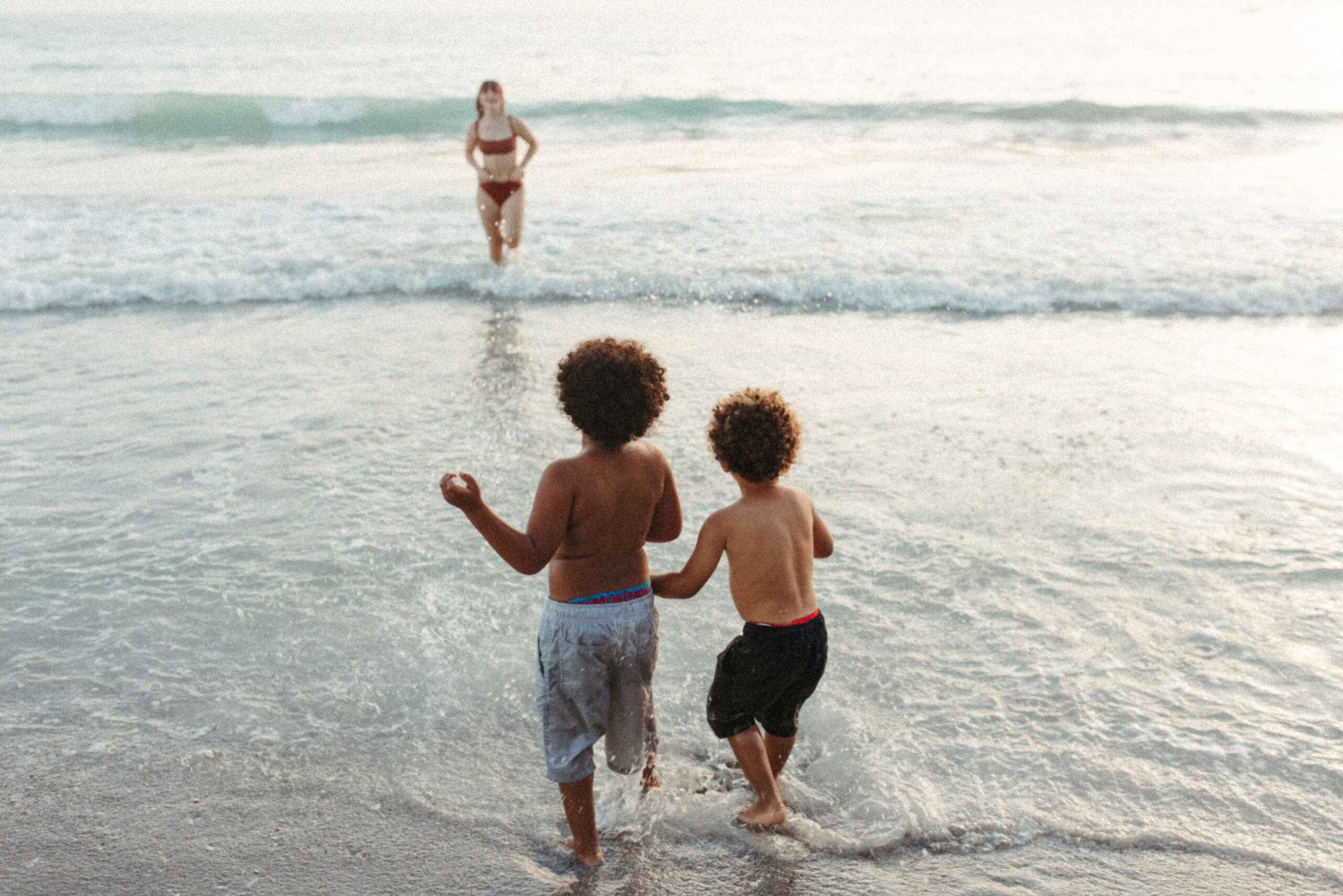 Two brothers wait for their sister by the ocean