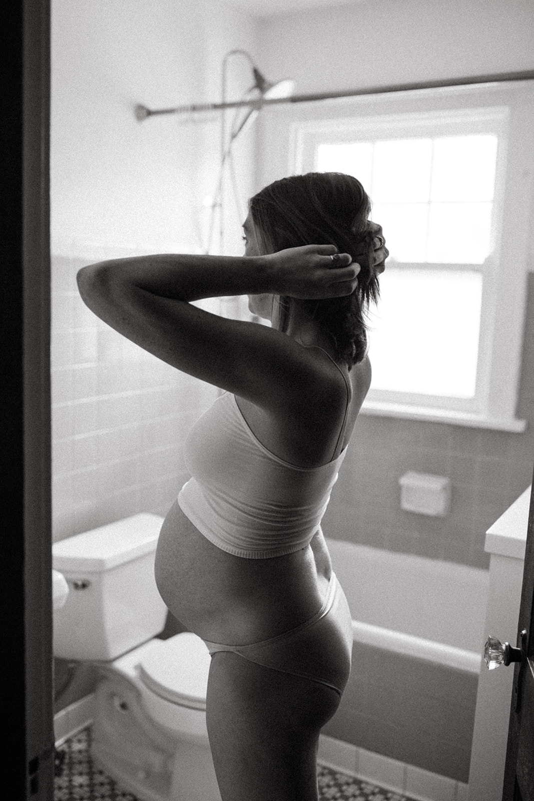 Pregnant mother looks at herself in the bathroom in Cincinnati, Ohio