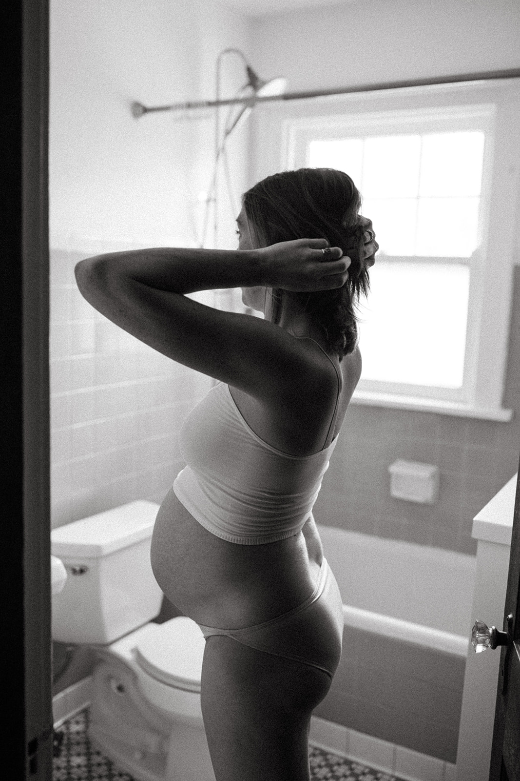 Family and Motherhood Photographer Lauren Neal Photography Pregnant mother looks at herself in the bathroom in Cincinnati, Ohio